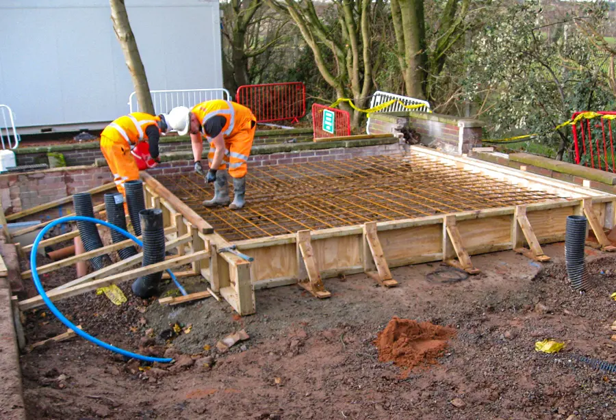 Two Hayward operatives fixing steel reinforcement in formwork on a groundworks site