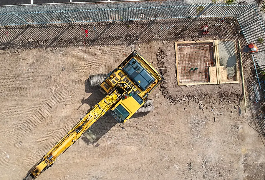 Aerial view of a Hayward civil engineering site — excavator alongside reinforced concrete foundations